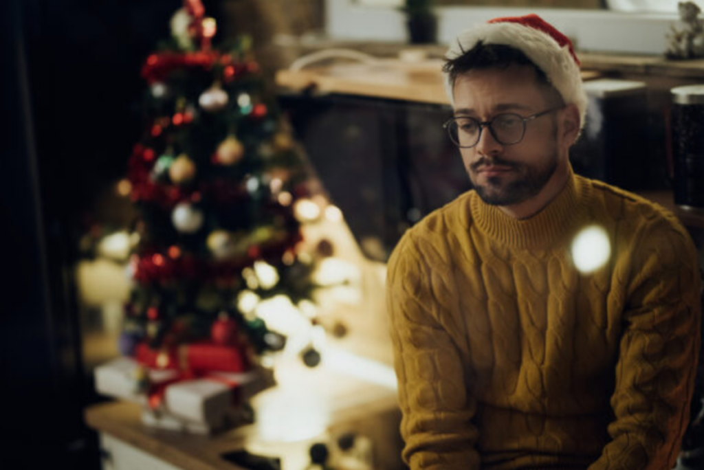 Young pensive man feeling lonely while spending New Year's eve alone at home.